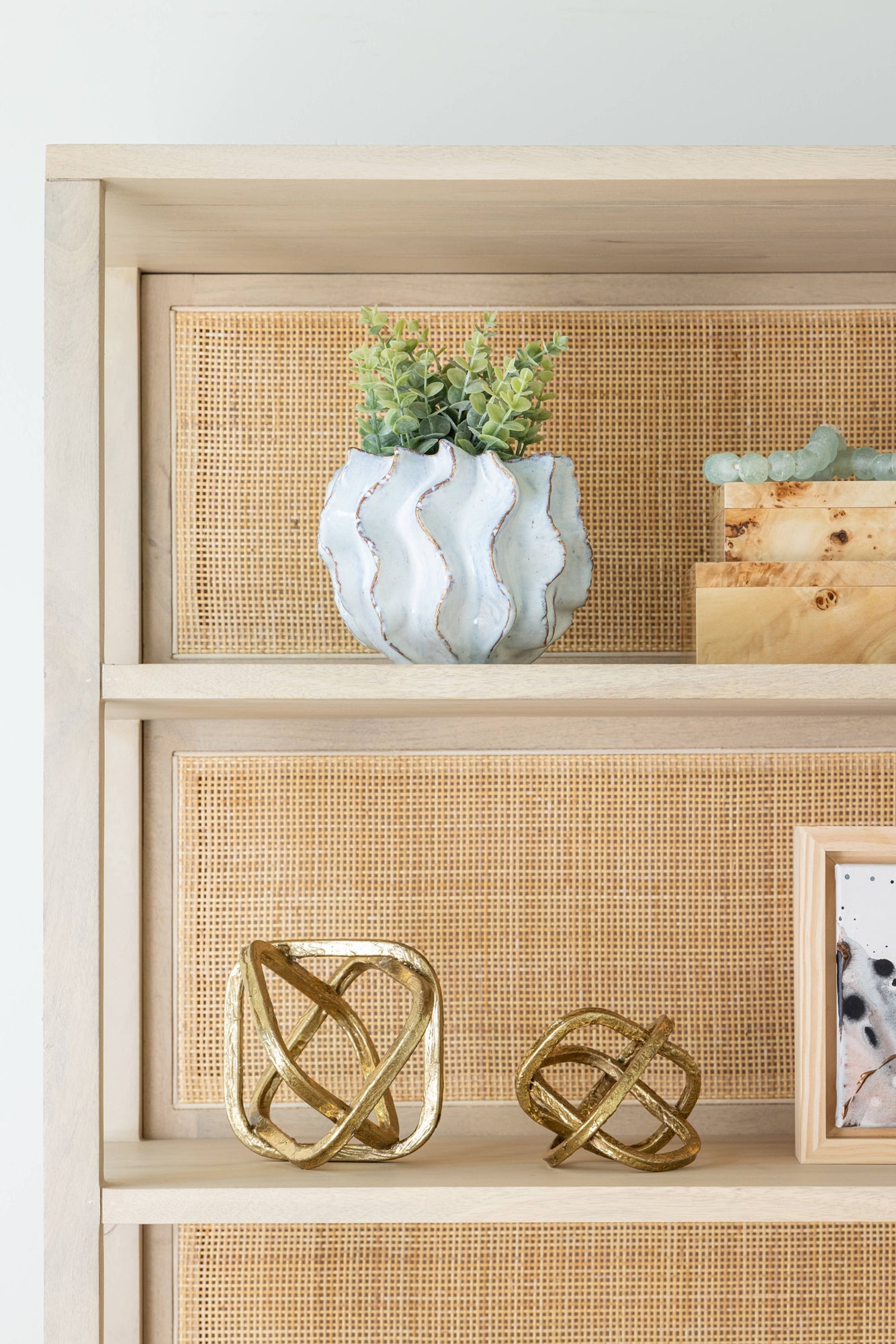 Dining room with blue wall paint. White ribbed candle holders beside a textured bowl vase with amber mums, light green hydrangeas and green millet draping over the vase. Candles and vase are sitting on an antique burl dining table. 